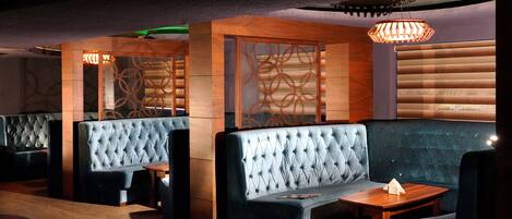 A restaurant with tufted seating, wooden partitions, and a table with a napkin.