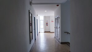 A hallway with a wooden floor, white walls, and doors on both sides. - THE SR Residence Lampang (Lampang)
