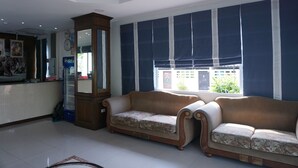 A living area with two sofas, a wooden cabinet, a refrigerator, and a large window with blue curtains. - THE SR Residence Lampang (Lampang)