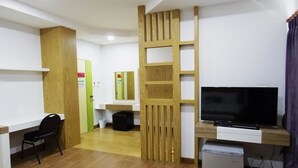 A hotel room with a wooden desk, a television, a small refrigerator, and a chair. - THE SR Residence Lampang (Lampang)
