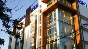 A multi-story building with a modern architectural design, featuring large windows and a prominent entrance. - THE SR Residence Lampang (Lampang)