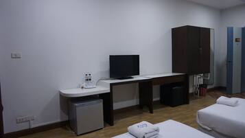 A hotel room with a bed, a desk with a television, a small fridge, a wardrobe, and a bathroom.