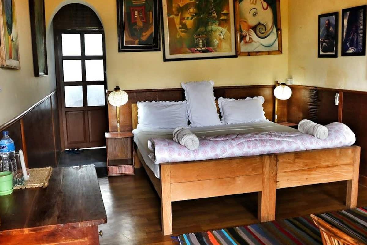 A wooden bed with white linens and pillows, a bedside table with a lamp, and a door with a window.