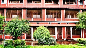 A two-story building with a red brick facade, multiple windows, and a small garden area with various plants. - Lake Twenty Thousand Farm and Retreat (Bharatpur)