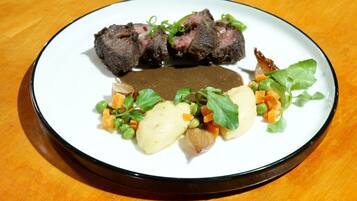 Un plato con bistec, puré de papas, guisantes, zanahorias y verduras de hoja.