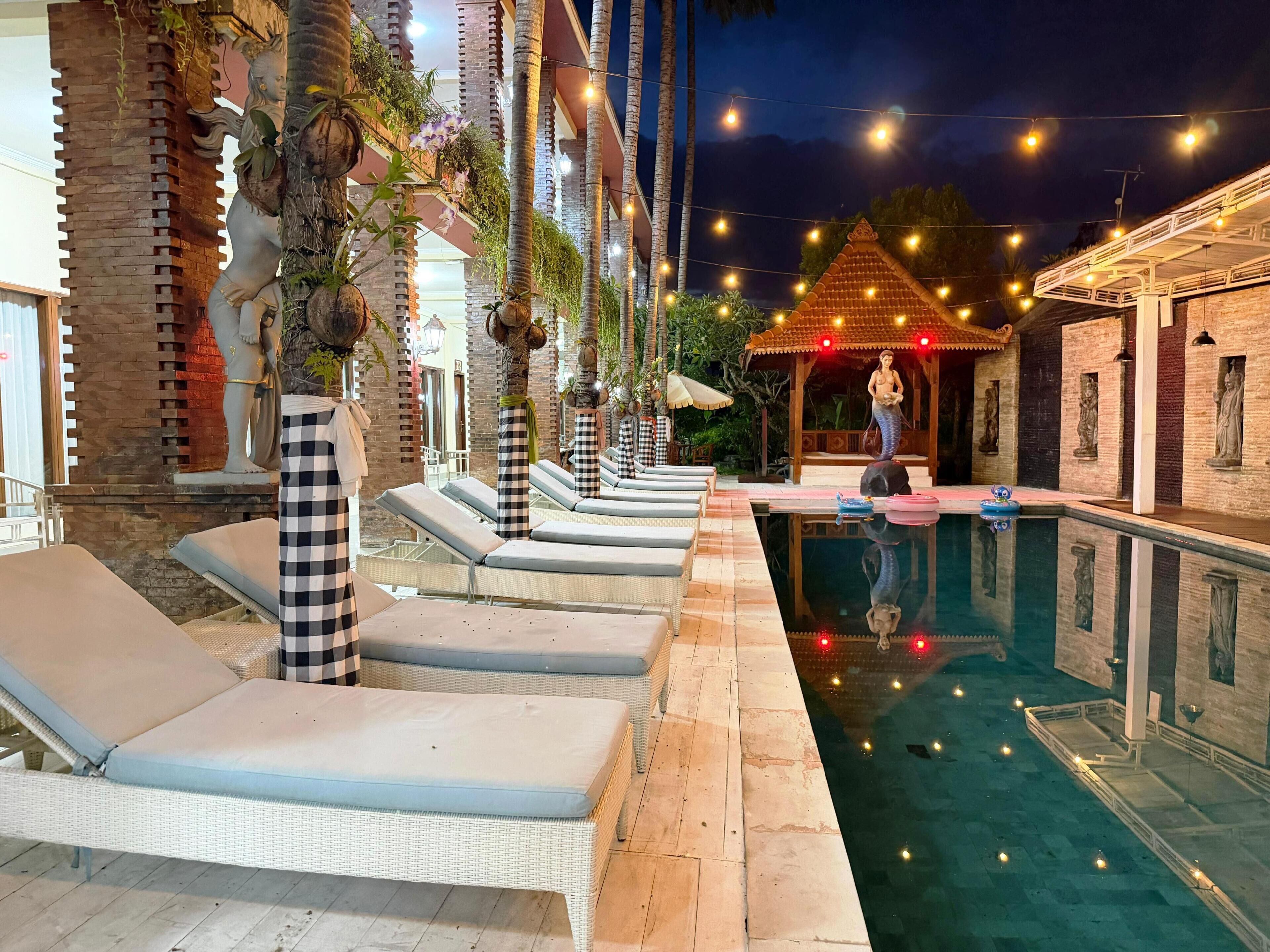 Un espace aménagé au bord de la piscine, avec des chaises longues, une petite piscine et des statues décoratives.
