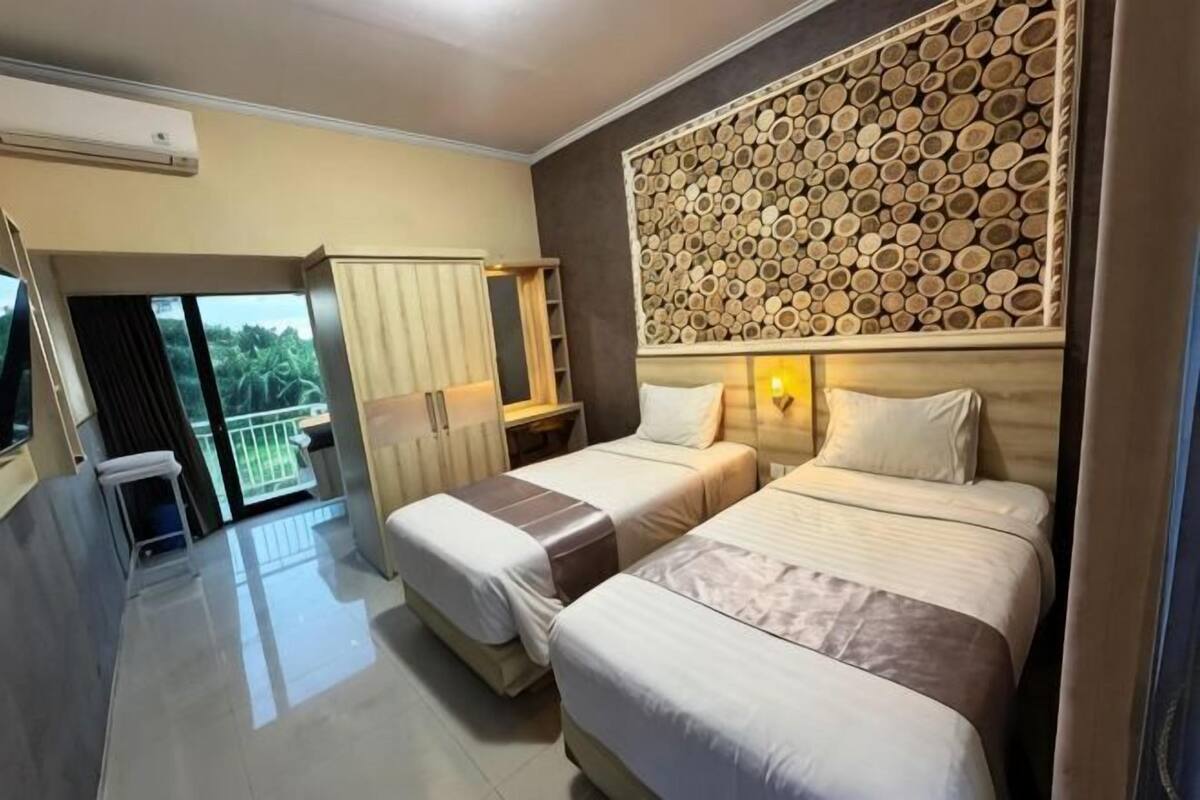 A hotel room with two beds, a balcony, a wall-mounted log pattern, and a TV.
