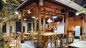 Restaurante com móveis de madeira, um relógio e uma geladeira.