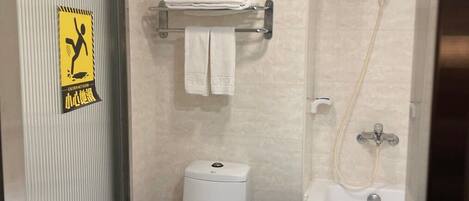 A bathroom with a toilet, a sink, and a shower. There is a towel rack with towels and a caution sign on the wall.