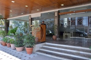 A hotel entrance with a wooden podium, potted plants, and a tiled floor. - Best Western Swing High Katra (Reasi)