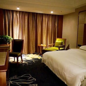 A hotel room with a bed, two chairs, a small table, and a plant. - Wangfu Cha'erkang Hotel (Changsha)