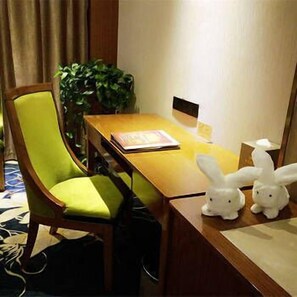 A hotel room with a wooden desk, a green chair, a plant, and two white bunny figurines. - Wangfu Cha'erkang Hotel (Changsha)
