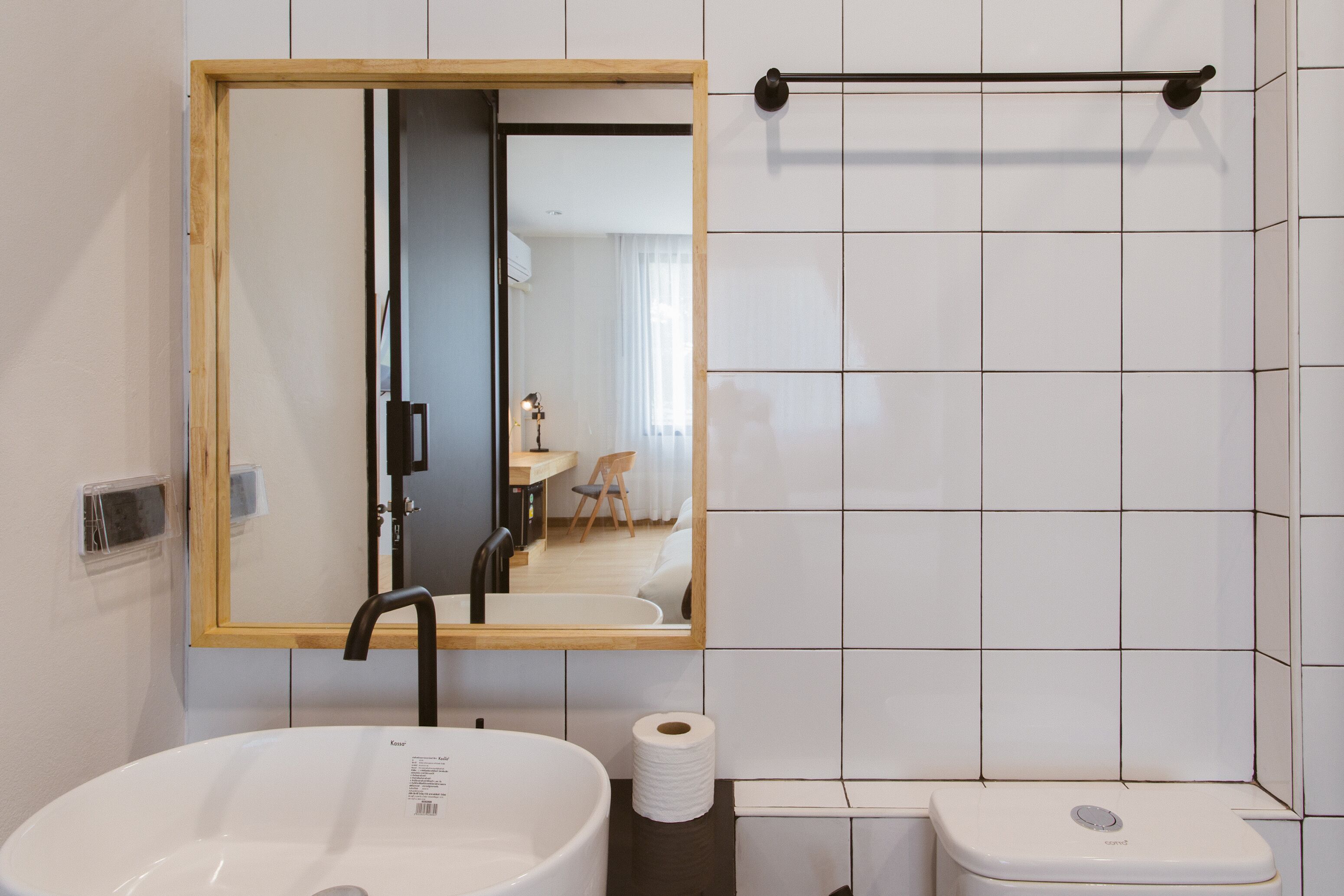 A bathroom with a large sink, a mirror, a toilet, and a towel rack.