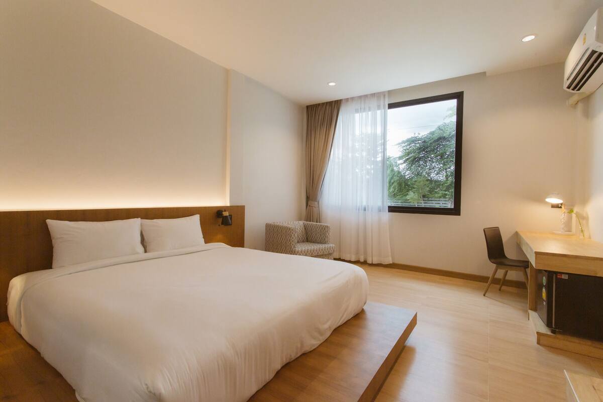 A modern hotel room with a large bed, a desk, and a chair.