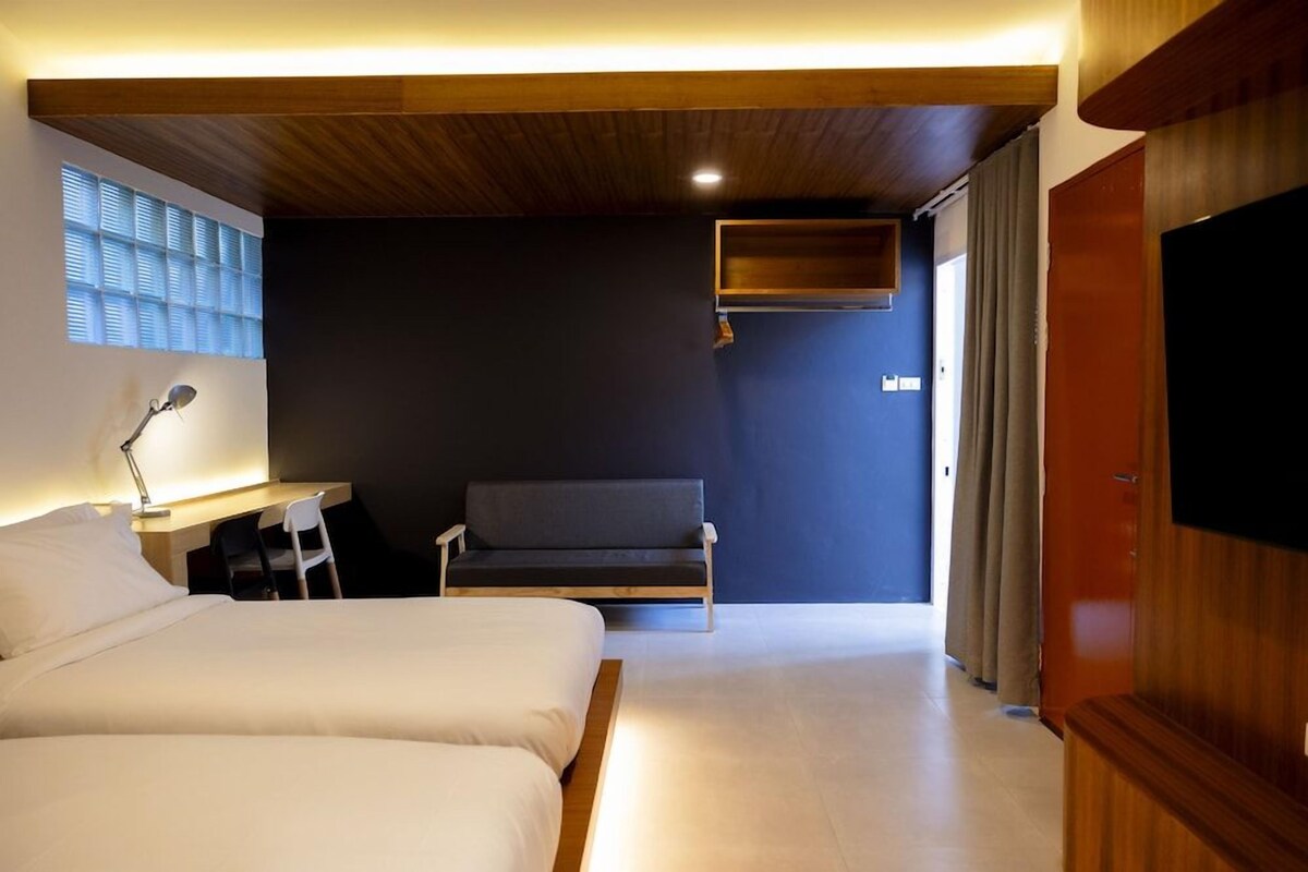 A modern hotel room with a bed, desk, chair, and a television.