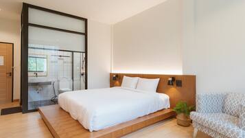 Une chambre moderne avec un grand lit, une plateforme en bois, un canapé et une plante en pot.