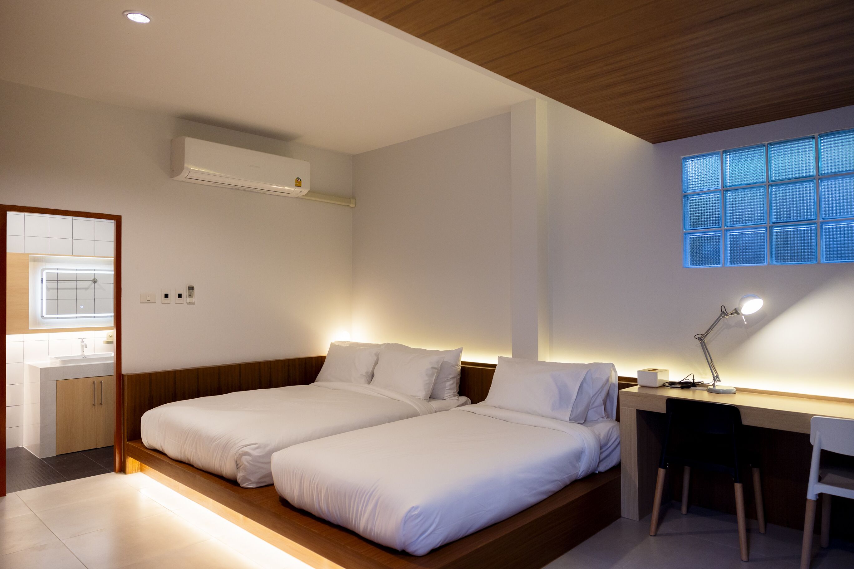 Un dormitorio moderno con dos camas, un escritorio y una ventana con diseño de cuadrícula.