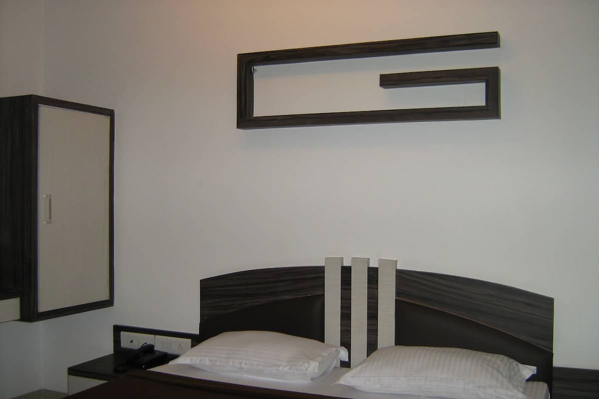 A hotel room with a bed, a nightstand, a telephone, and a wall-mounted mirror.