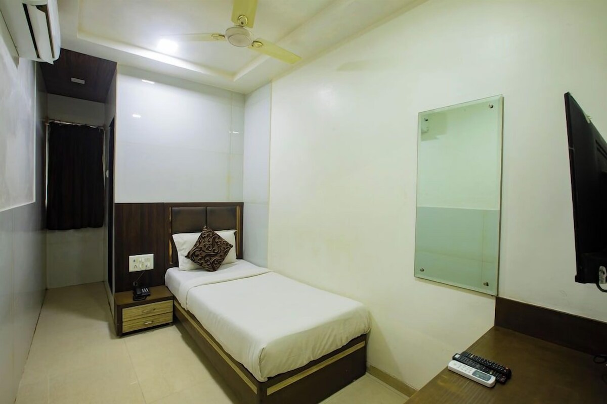 A bedroom with a bed, bedside table, nightstand, and a ceiling fan.