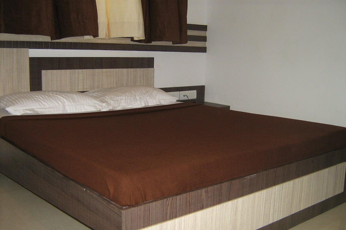 A single bed with a wooden frame and a brown mattress.