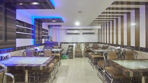 Un restaurante con un interior moderno, que presenta suelo de tablones de ajedrez, sillas de metal y mesas.