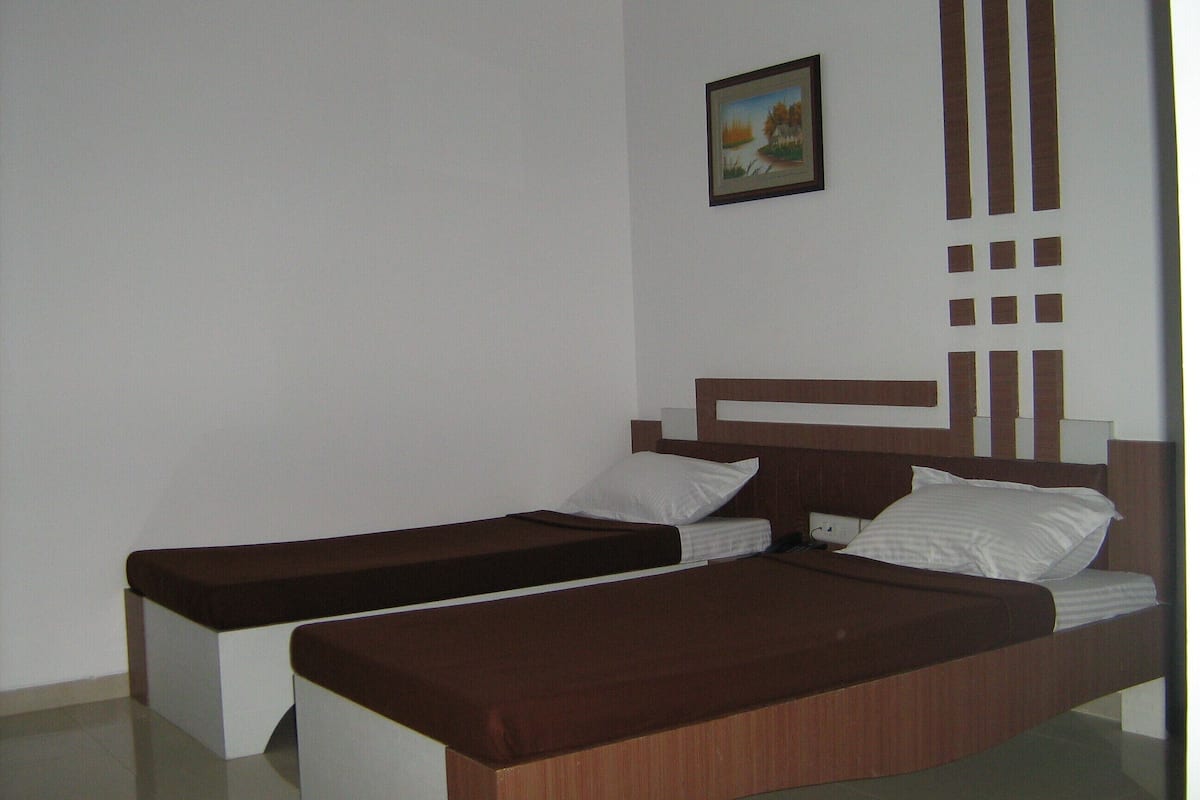 A double bed with a wooden headboard, two pillows, and a brown blanket.