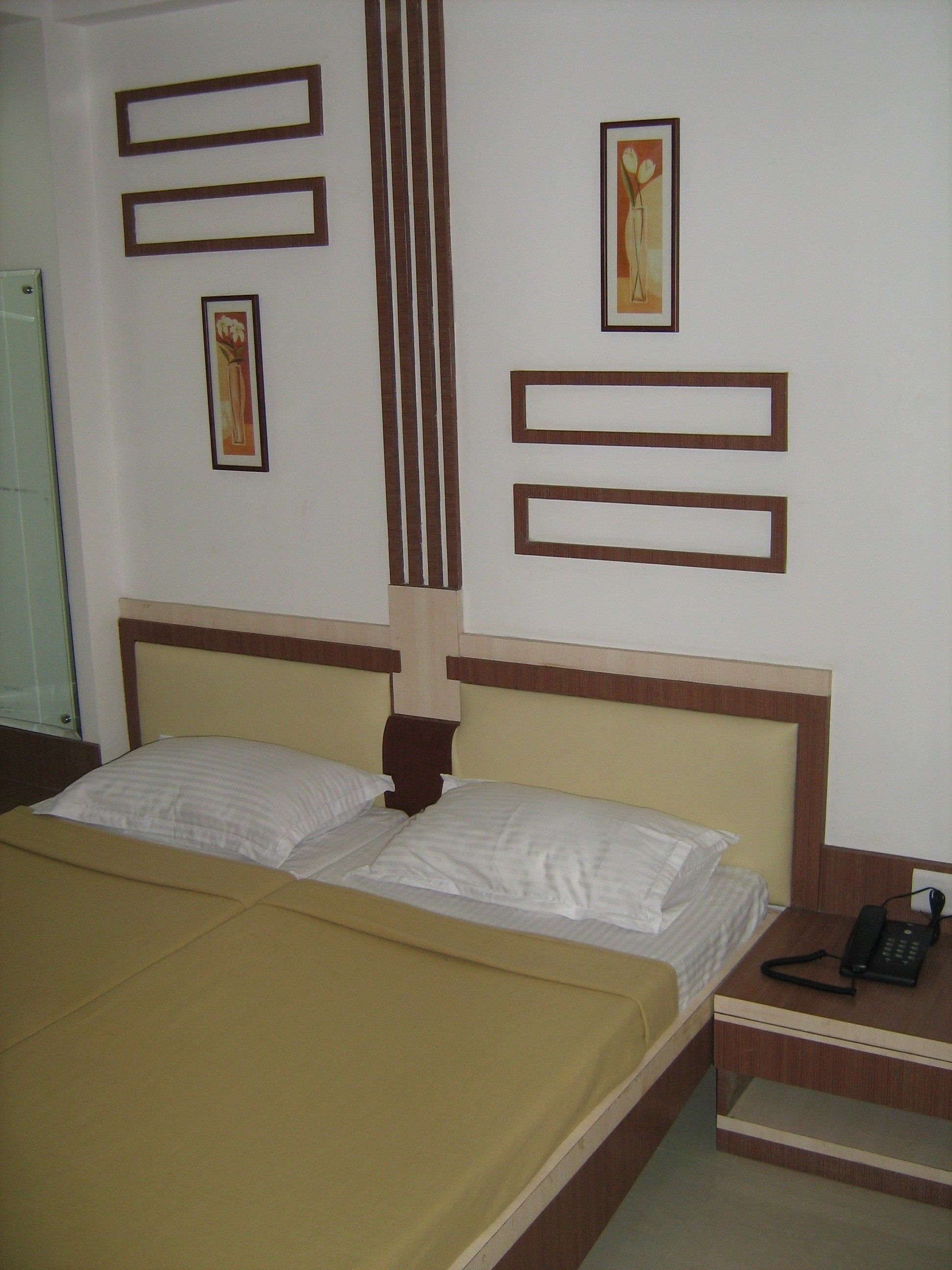 A hotel room with a bed, a bedside table with a phone, and decorative wall panels.