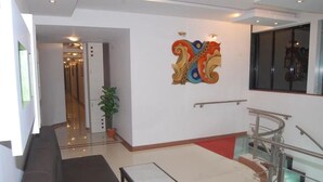 Un vestíbulo moderno con una escalera, un sofá, una mesita y un elemento decorativo en la pared.