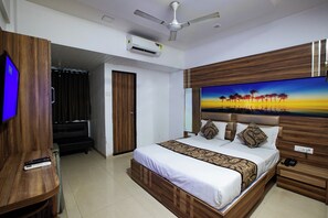 A hotel room with a bed, a TV, a ceiling fan, and an air conditioning unit. - Hotel Apex (Navi Mumbai)