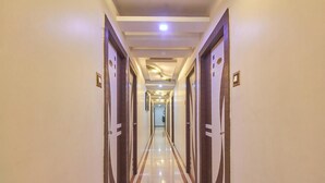 Pasillo de hotel con puertas a ambos lados, una lámpara central y suelo reflectante.