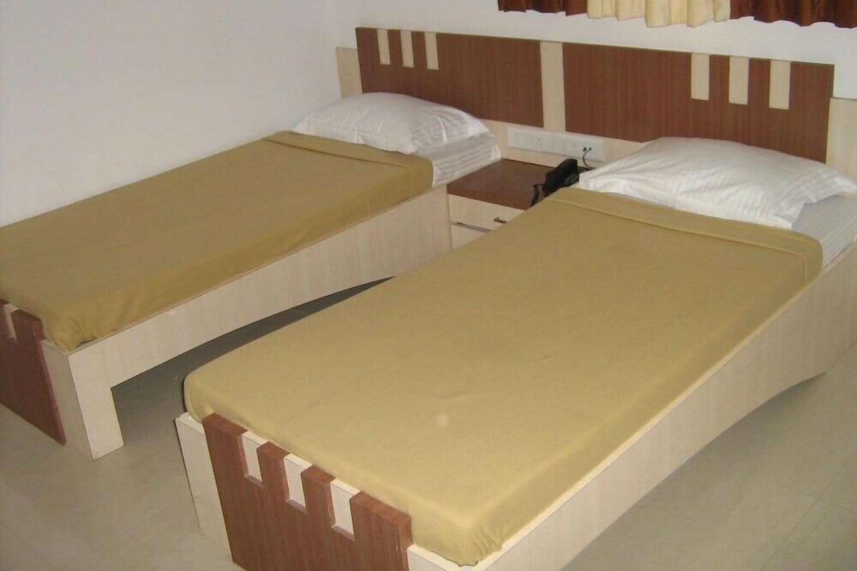 Two single beds with wooden headboards, beige bedding, and a brown curtain.