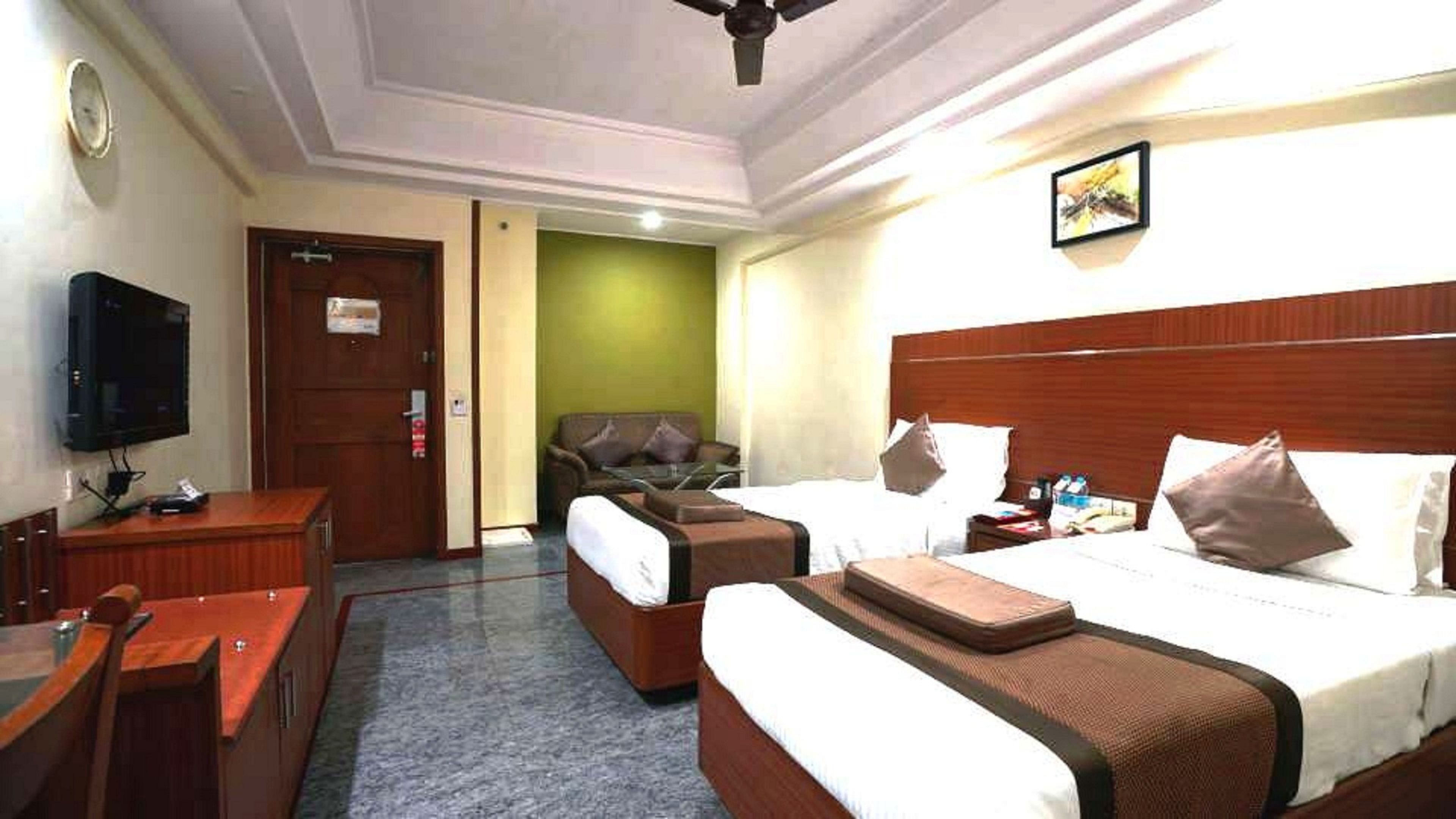A hotel room with a bed, a sofa, a TV, and a desk.