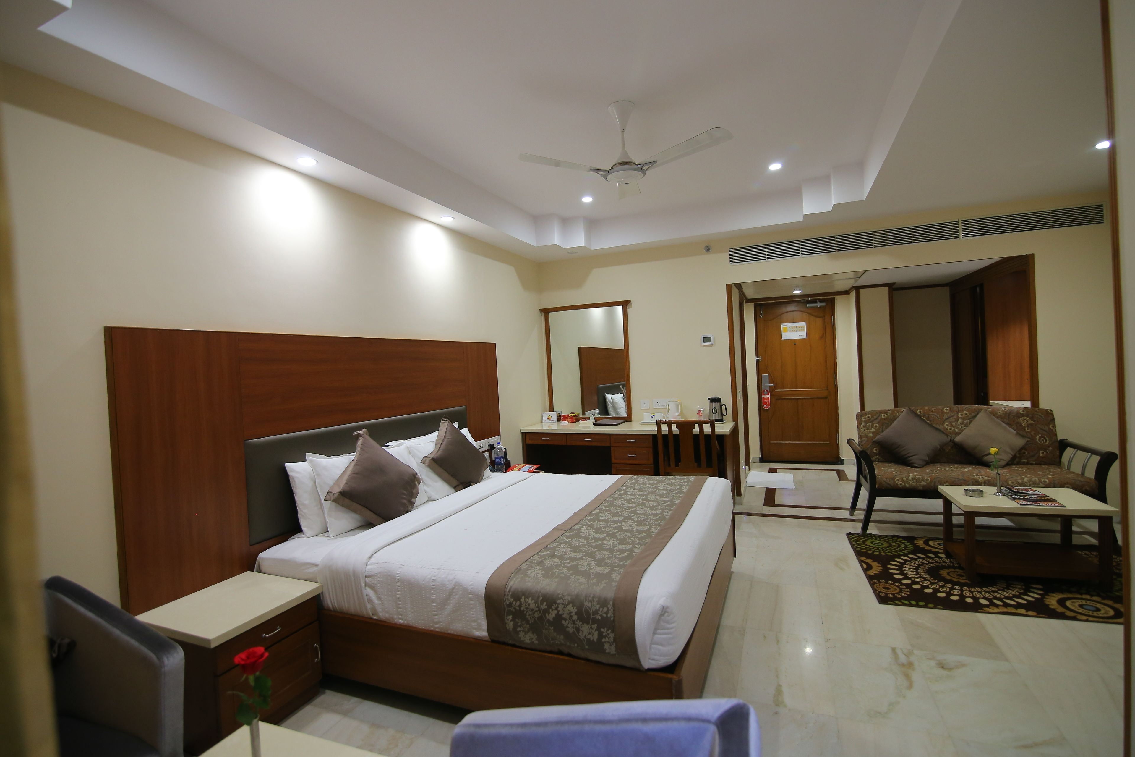 A hotel room with a bed, bedside table, chair, desk, and a sofa.