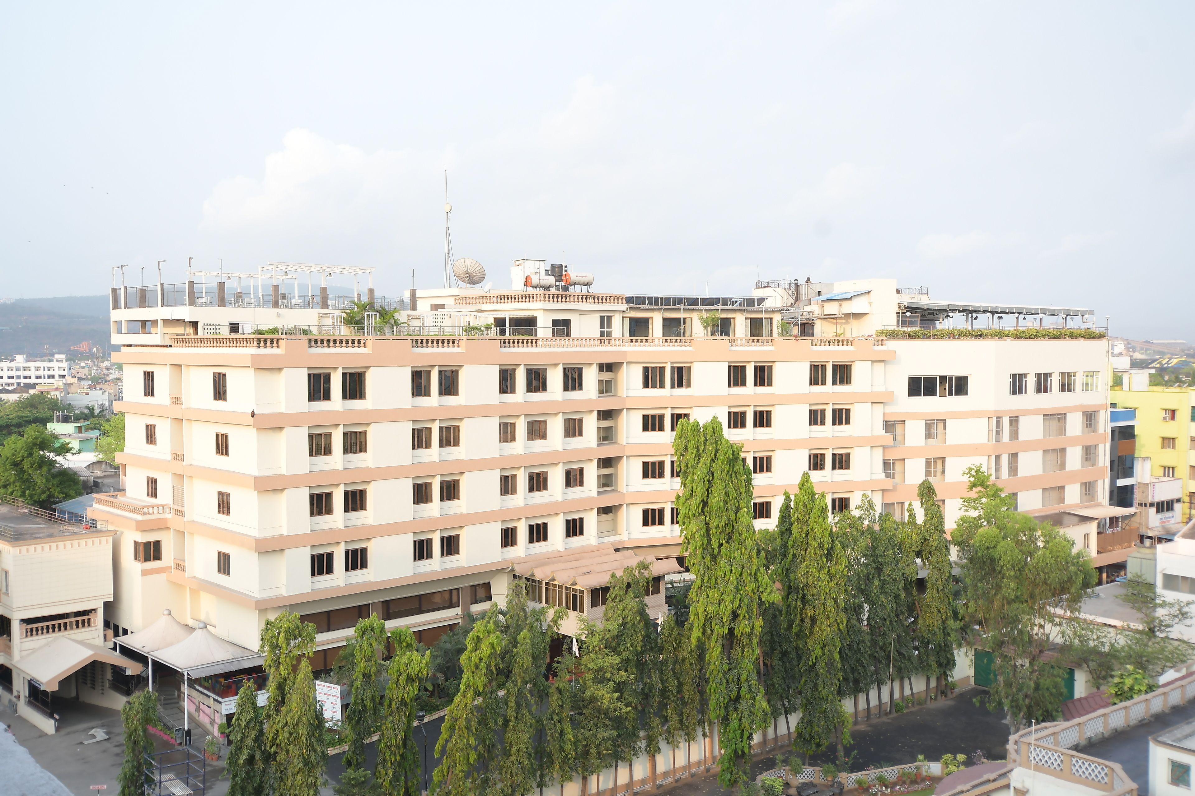 A multi-story building with a flat roof, several balconies, and a satellite dish.