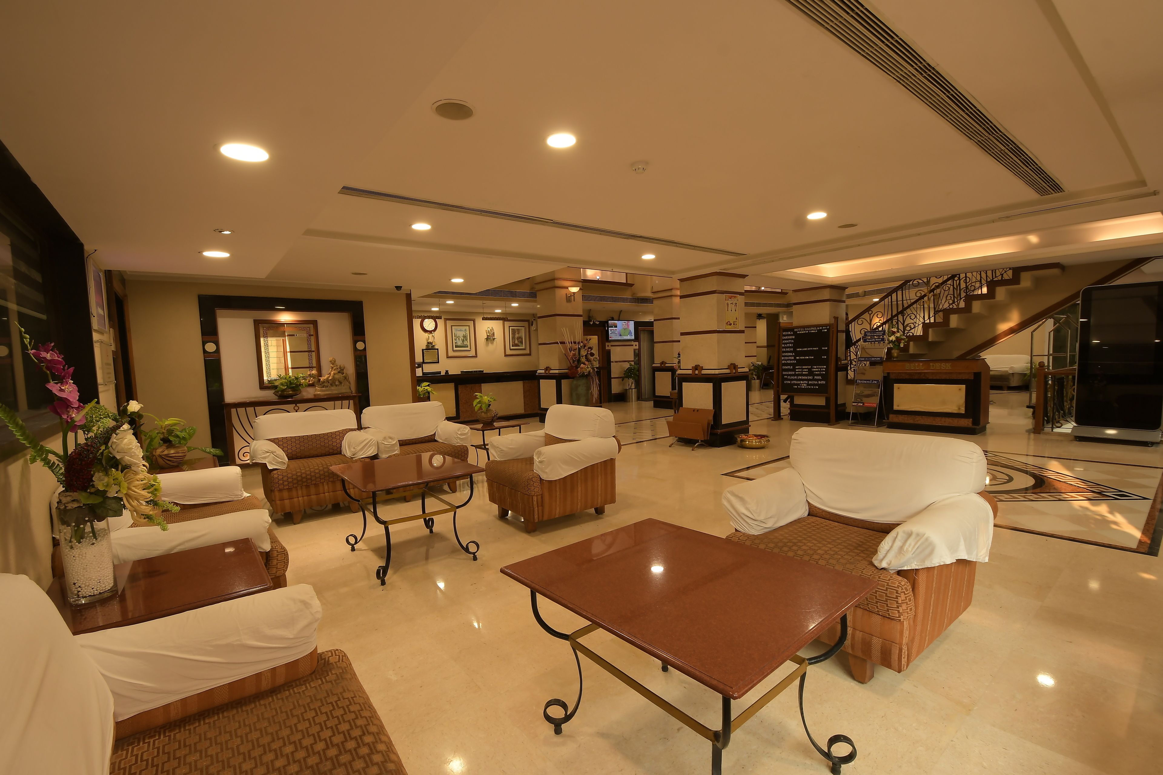 A spacious lobby with multiple seating areas, a reception desk, and a staircase leading to upper floors.