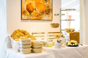 A buffet setup with various food items and serving utensils, a painting on the wall, and a modern light fixture. - Regiohotel Berghotel Ilsenburg (Ilsenburg)