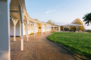 A covered outdoor area with a brick pathway leading to a grassy lawn. - Regiohotel Berghotel Ilsenburg (Ilsenburg)