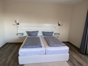 A double bed with a white headboard and two bedside tables, each with a lamp. - Regiohotel Berghotel Ilsenburg (Ilsenburg)