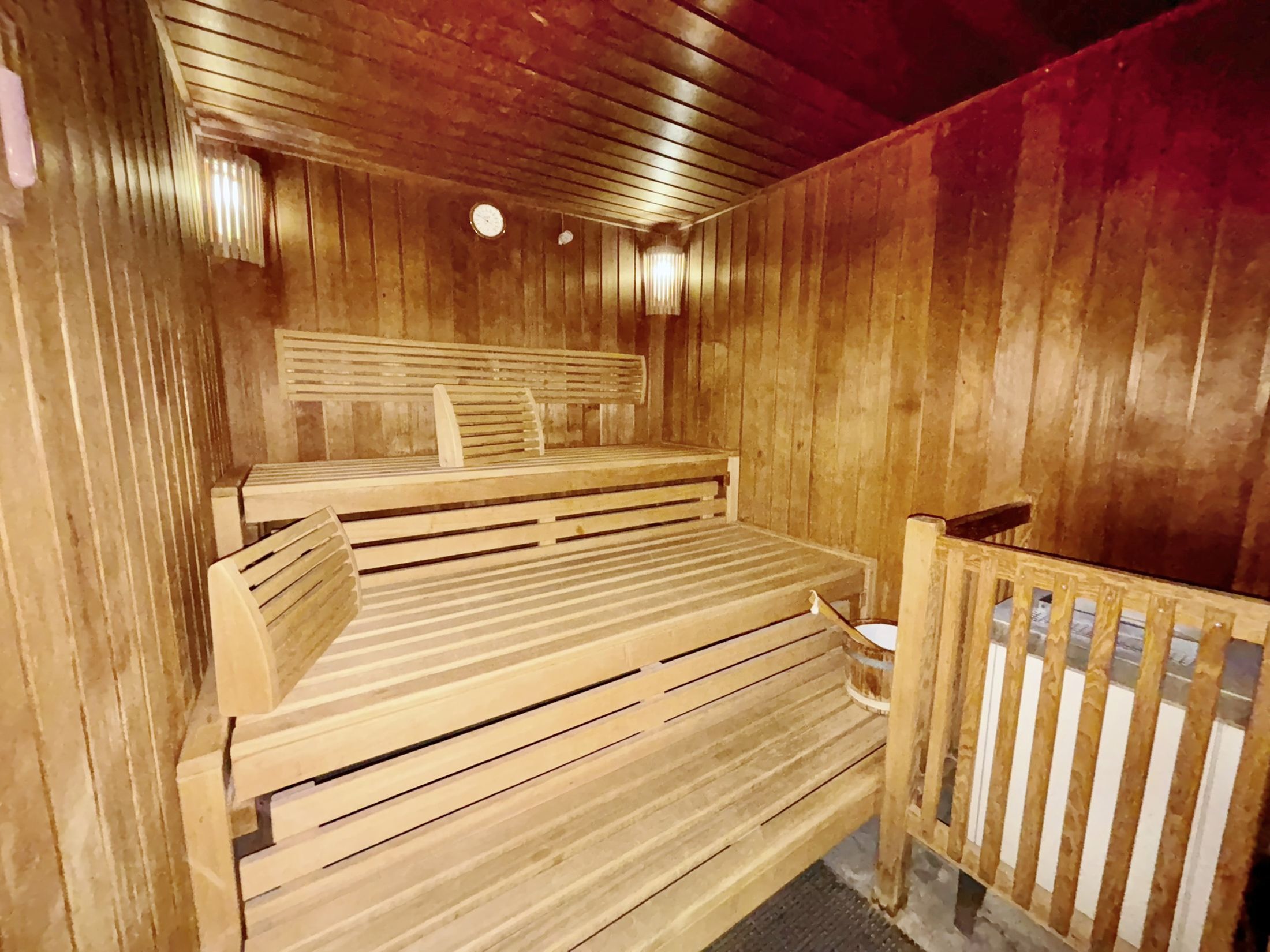 Een houten sauna met banken en een houten leuning.