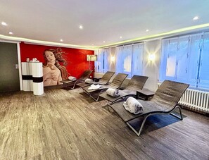A modern waiting area with lounge chairs, a large mural, and a view of the outdoors.