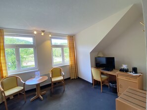 A hotel room with a desk, two chairs, a television, and a small table. - Regiohotel Berghotel Ilsenburg (Ilsenburg)