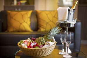 A fruit basket with a pineapple and grapes on a table, two champagne flutes, and a bottle of champagne in a silver bucket. - Regiohotel Berghotel Ilsenburg (Ilsenburg)