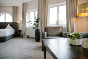 A hotel room with a bed, a sofa, a table, and a potted plant. - Regiohotel Berghotel Ilsenburg (Ilsenburg)