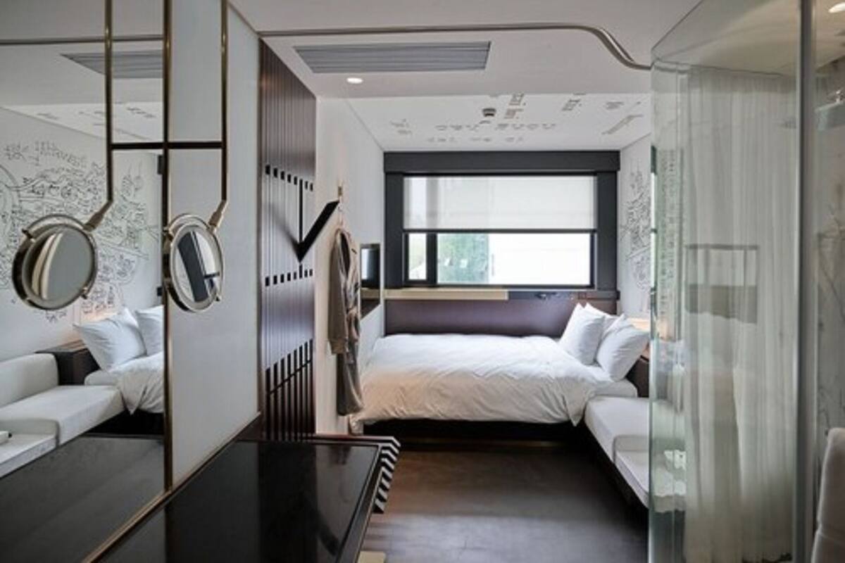 Een moderne slaapkamer met een bed, een bureau en een groot raam.