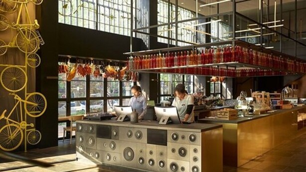 A modern bar area with a central counter, large windows, and a bicycle decoration.