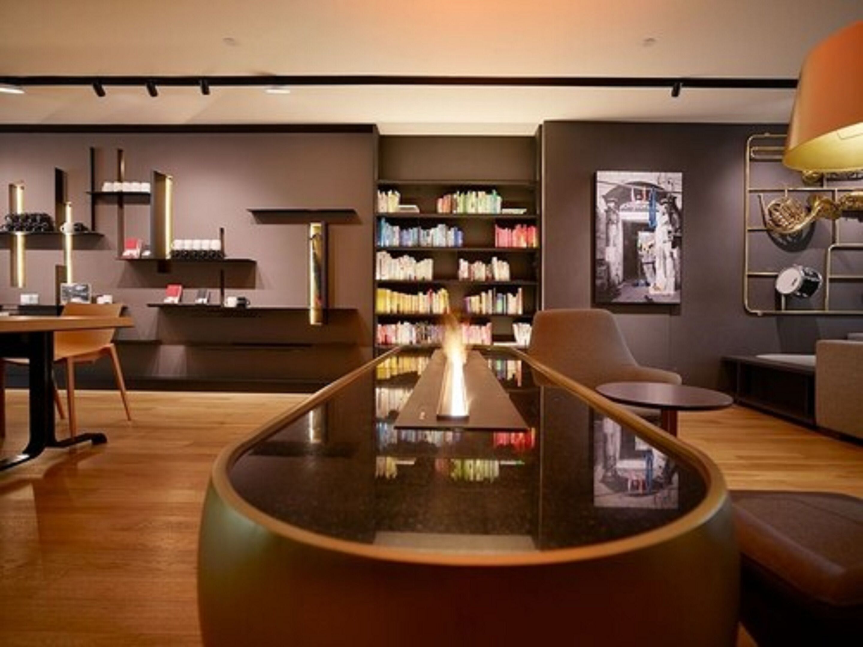 A modern interior with a central table, bookshelves, and seating areas.