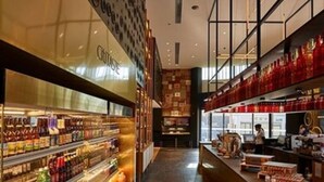 A modern interior with a long counter displaying various food items and a glass display case with beverages.