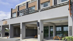 A modern building with a flat roof, large windows, and a covered outdoor area with a table and chairs. - GOODHOUSE (Hengchun)