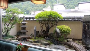 A traditional Japanese garden with a stone lantern, a small pagoda, and a koi pond. - Kinugawa Kokusai Hotel (Nikko)