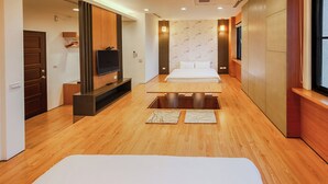 Une chambre d’hôtel avec un plancher en bois, un lit, une télévision et une fenêtre.